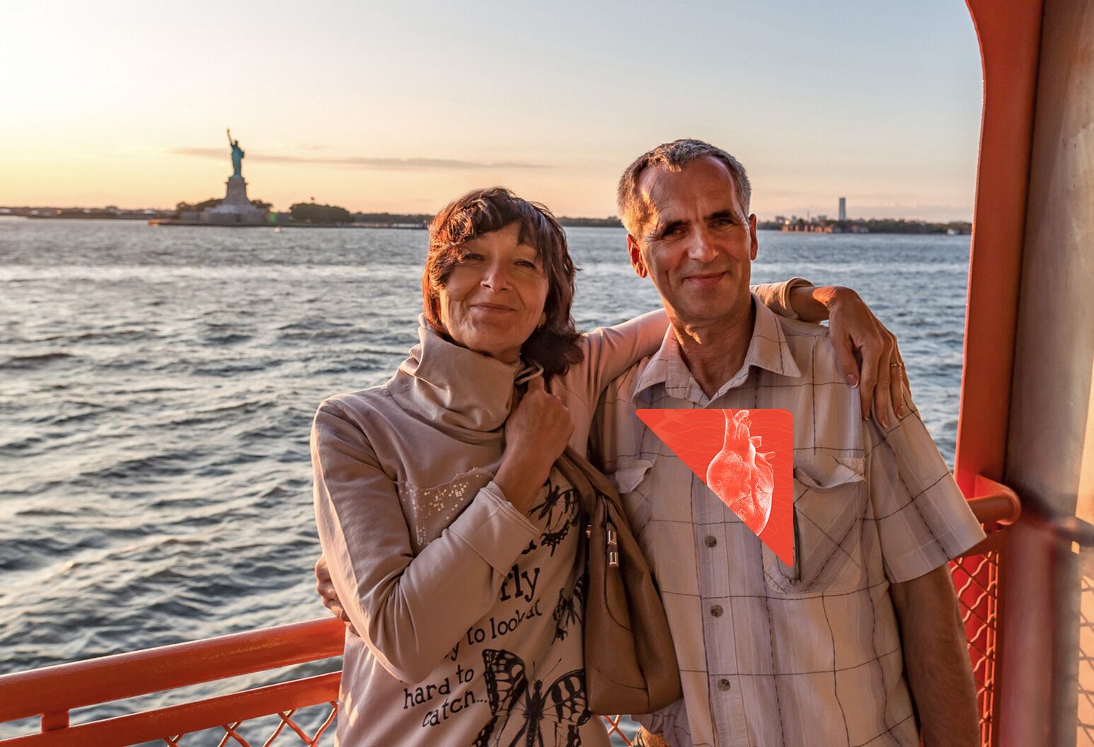 Woman with arm around man, standing on ferry near statue of liberty
